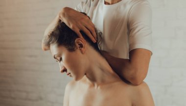 Masaj masasında yatan genç bir kadının omuzlarına masaj yapan kadın masörlerin elleri. Fizik tedavi konsepti, boyun basınç noktası..