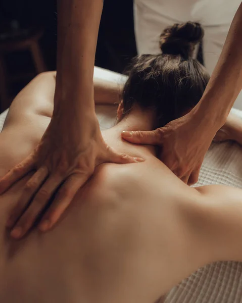 Hands of female chiropractor massaging shoulders of young woman lying on massage table. Concept of physical therapy treatment ,neck pressure point.