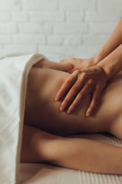 Beyaz arka planda masaj masasında yatan genç bir kadının karın masajı yapan kadın kayropraktik uzmanının elleri. İçsel masaj. Fizik tedavi konsepti, boyun basınç noktası..