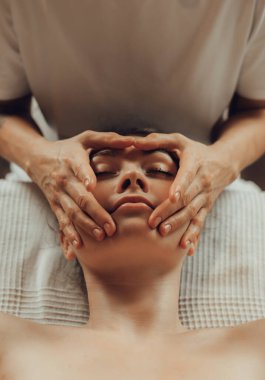 Masaj masasında yatan genç bir kadının masaj yapan kadın masörünün elleri. İçsel masaj. Fizik tedavi konsepti, boyun basınç noktası..