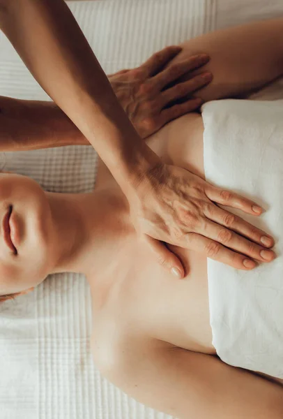 Hands of female chiropractor massaging shoulders of young woman lying on massage table. Concept of physical therapy treatment ,neck pressure point.