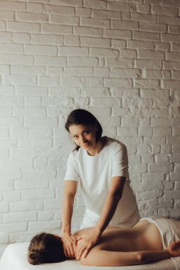 Masaj masasında yatan genç bir kadının sırtına masaj yapan kadın masörlerin elleri. Masöz, müşterinin fileto kasığına vakum fincanı uyguluyor. Fizik tedavi konsepti, boyun basınç noktası..