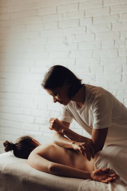 Masaj masasında yatan genç bir kadının sırtına masaj yapan kadın masörlerin elleri. Masöz, müşterinin fileto kasığına vakum fincanı uyguluyor. Fizik tedavi konsepti, boyun basınç noktası..