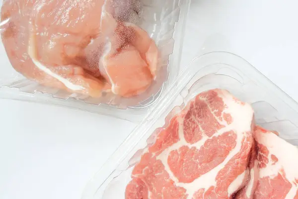 Fresh raw meat in package in plastic box, Close-up of meat in plate over light background.