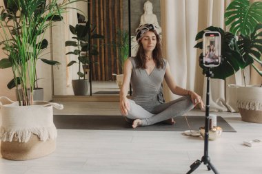 Akıllı telefondan canlı yayında yoga dersi. Güzel bir kadın evde eğitim görüyor ve dijital tablette online dersler izliyor. Antika tonlu. Yumuşak odak bulanık ve gürültü efekti.