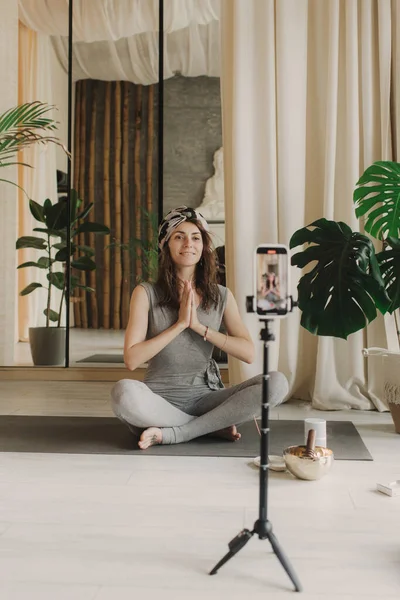Live streaming on a smartphone - online yoga lesson. Beautiful woman training at home and watching online lessons in the digital tablet. Vintage tonned. Soft focus blurred and noise effect.