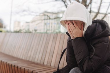 Üzgün ve depresif bir kız akıllı telefon tutuyor ve kafasını tutuyor. Üniversite öğrencisi lisede depresyondan muzdarip. Yalnız bir genç..