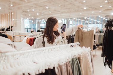 Koreli genç kız alışveriş merkezinde şık kıyafetler seçiyor ve satın alıyor. Perakende ve tüketim. Satış promosyonu ve alışveriş konsepti. Bir serinin parçası.
