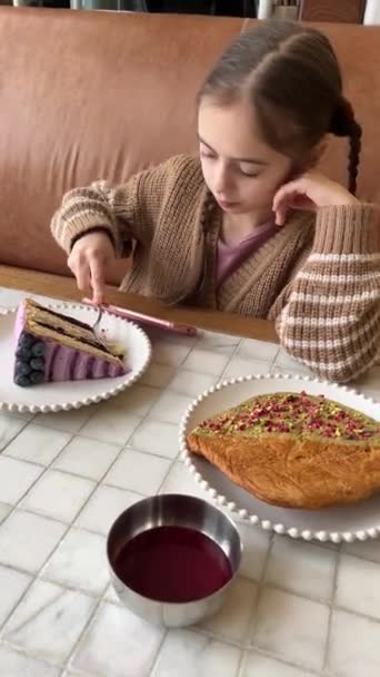 朝食を食べながら携帯電話を使っている美しい女の子 カフェで食べ物を食べながらビデオゲームをしているかわいい10代の少女 リアルタイム映像 ジェネレーションアルファ — ストック動画