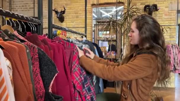女人的手在购物中心里碰到了一堆衣服 在服装店里 女性手拉起衣架选择衣服的特写镜头 促销和购物概念 免版税图库视频