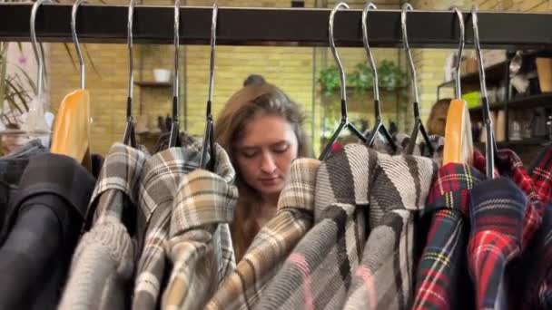 女人的手在购物中心里碰到了一堆衣服 在服装店里 女性手拉起衣架选择衣服的特写镜头 促销和购物概念 免版税图库视频