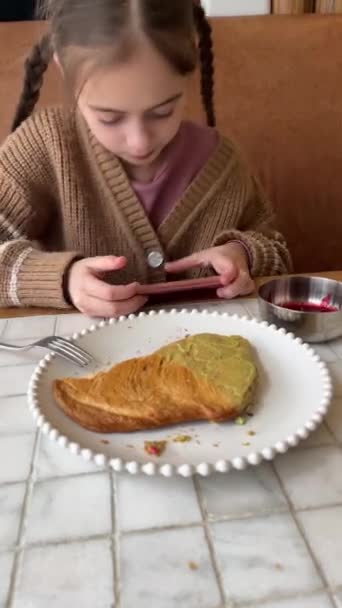 Vakker Jente Som Bruker Mobiltelefon Mens Spiser Frokost Søt Pre royaltyfrie gratis stockopptak