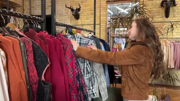 女人的手在购物中心里碰到了一堆衣服 在服装店里 女性手拉起衣架选择衣服的特写镜头 促销和购物概念 视频剪辑