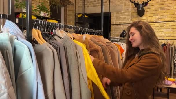 女人的手在购物中心里碰到了一堆衣服 在服装店里 女性手拉起衣架选择衣服的特写镜头 促销和购物概念 图库视频片段