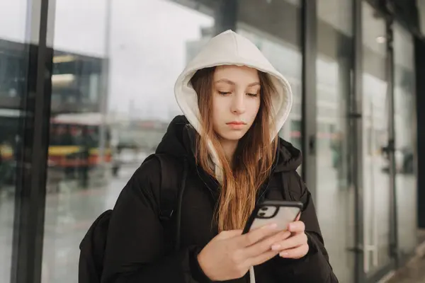 秋冬シーズンに街でブログをするためのスマートフォンを保持するカジュアルなウェアで少女の半分の長さの肖像画 ティーン サーフィン インターネット ストック写真