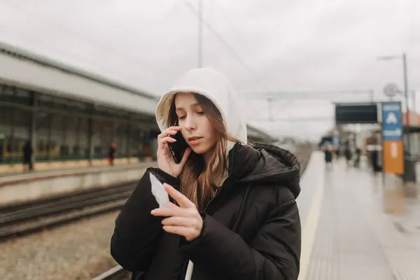 スマートフォンマップ ソーシャルメディアチェックイン またはチケット予約を使用して電車の駅で観光十代の少女 モダンな旅行アプリテクノロジー 孤独な旅行者 冬の休暇鉄道アドベンチャーコンセプト ストック画像
