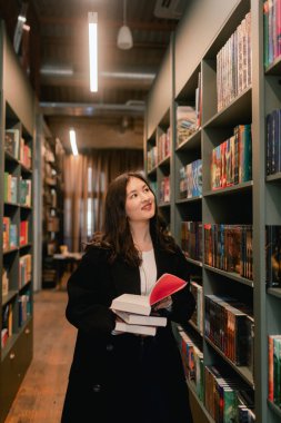 Güzel genç nesil Z Koreli kız kitapçıda kitap seçiyor. Eğitim eğitimi konsepti. Bir serinin parçası.