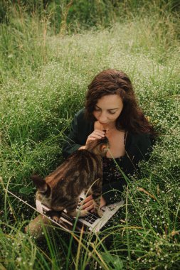 Eko-çiftlikte kedisi olan bir kadın bilgisayar kullanıyor. Çevrimiçi sohbet. Doğa üzerinde boş zaman geçir. Evden çalışma kavramı, yavaş yaşam, bağlı kalma, sosyal mesafeler, internet. Dizinin bir parçası.