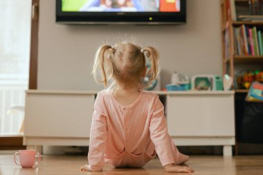 Oyuncak oyuncaklarla oynayan ve oyun odasında televizyonda çizgi film izleyen mutlu bebek portresi. Çocuklar ve teknoloji konsepti. Elektronik cihazlı Alfa Jenerasyonu ve modern teknoloji. Dizinin bir parçası.