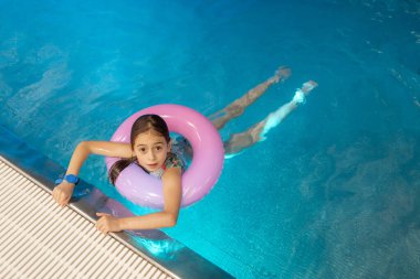 Yüzme havuzunda yüzdükten sonra küçük yüzücü kızın yakın plan portresi. Küçük kız suda boğulmaktan korkuyor. Uzayı kopyala Çocuk güvenliği kavramı havuz suyunun yanında..