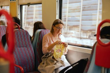 Toplu taşımacılıkta yün kullanarak örgü işi yapan çekici bir kadın. Zamanda yolculuğun tadını çıkaran rahat bir kadın. Seyahat konsepti üzerinde yaratıcı aktiviteler. Uzayı kopyala Dizinin bir parçası.