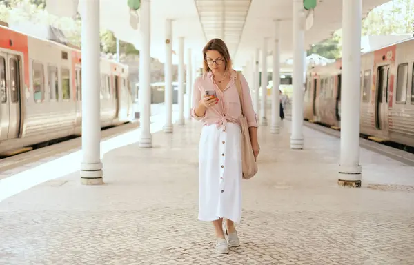 stock image City travel concept. Tourist Woman looking at a ticket on her phone and waiting for transport at station, passenger books a ticket online through in the application. Copy space. Part of the series.