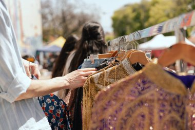Perakende mağazasında farklı renklerde moda kıyafetleri seçiyor. Dışarıda eski giysiler olan bit pazarı. Geri Dönüşüm Konseptini Azalt.