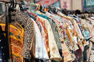 Perakende mağazasında farklı renklerde moda kıyafetleri seçiyor. Dışarıda eski giysiler olan bit pazarı. Geri Dönüşüm Konseptini Azalt.