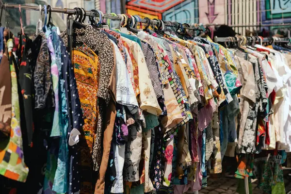 Perakende mağazasında farklı renklerde moda kıyafetleri seçiyor. Dışarıda eski giysiler olan bit pazarı. Geri Dönüşüm Konseptini Azalt.