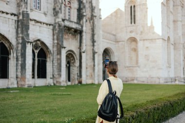 Orta yaşlı gezgin kadın, Belem, Lizbon, Portekiz 'deki Monteiro dos Jeronimo' nun güzel bir manzarasının cep telefonuyla fotoğraflarını çekiyor. Seyahat ve solo turizm konsepti. Dizinin bir parçası.