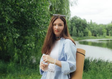 Yoga yaptığı için yoga minderli Koreli kız parkta meditasyon yapacak bir yer arıyor. Doğayla bütünlük ve kendine yeten konsept. Dizinin bir parçası.