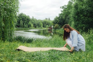 Yoga antrenmanı için yoga minderli Koreli kız parkta meditasyon yapıyor. Doğayla bütünlük ve refah kavramı. Dizinin bir parçası.