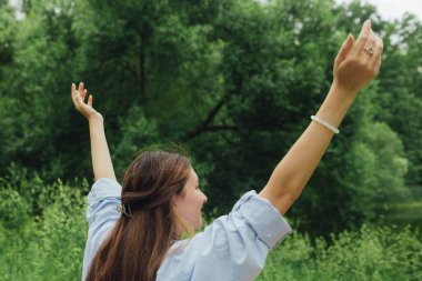 Koreli kız parkta yoga meditasyonu yapmak için ellerini gökyüzüne uzatıyor. Doğayla bütünlük ve refah kavramı. Dizinin bir parçası