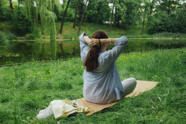 Yoga antrenmanı için yoga minderli Koreli kız parkta meditasyon yapıyor. Doğayla bütünlük ve refah kavramı. Dizinin bir parçası.