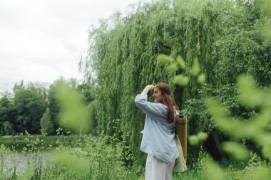 Yoga yaptığı için yoga minderli Koreli kız parkta meditasyon yapacak bir yer arıyor. Doğayla bütünlük ve kendine yeten konsept. Dizinin bir parçası.