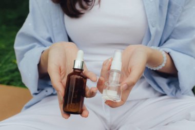 Parkta gerekli yağlı şişeyle kadının ellerini kapat. Doğayla bütünlük ve refah kavramı. Dizinin bir parçası. Saç bakım ürünlerinin saç uçları ya da güneş koruması kavramı.