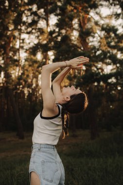 Doğayla bütünlük ve refah kavramı. Yoga antrenmanı için yoga minderiyle eğlenen aşırı neşeli kadın parkta meditasyon yapıyor. Kadın insan kavramı ve sağlıklı doğal yaşam tarzı. Dizinin bir parçası.