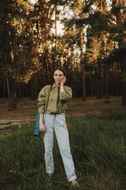 Doğayla bütünlük ve refah kavramı. Yoga antrenmanı için yoga minderiyle eğlenen aşırı neşeli kadın parkta meditasyon yapıyor. Kadın insan kavramı ve sağlıklı doğal yaşam tarzı. Dizinin bir parçası.