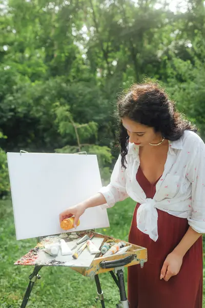 Kadın sanatçılar parkta bir resim çizerler. Farkındalık, sanat terapisi, yaratıcılık kavramı. Doğada plein hava boyama işlemi. Bir tablonun adım adım oluşturulmasını gösteren bir dizi fotoğraf.