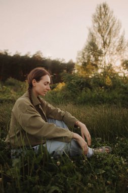 Doğayla bütünlük ve refah kavramı. Yoga antrenmanı için yoga minderiyle eğlenen aşırı neşeli kadın parkta meditasyon yapıyor. Kadın insan kavramı ve sağlıklı doğal yaşam tarzı. Dizinin bir parçası.