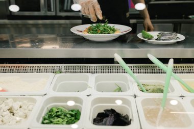 Tezgahtaki metal kaplarda yemek yapmak için farklı malzemeler içeren modern bir restoran. Yemek ve açık büfe konsepti.