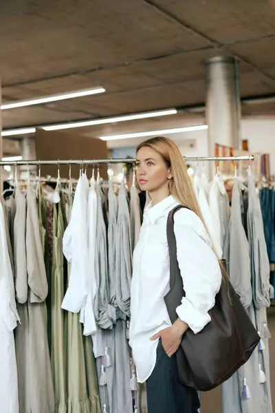 stock image Middle aged woman chooses a dress made of natural linen in a shopping mall. Close-up of lady plucked hanger choosing clothes in clothing store. Sale promotion and shopping concept. Part of the series.