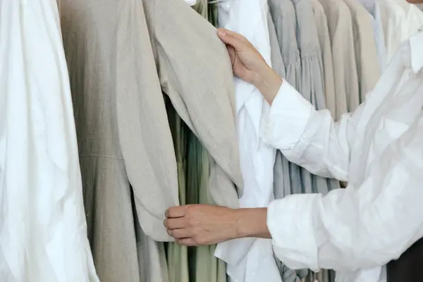 stock image Close-up of female hands plucked hanger choosing clothes in clothing store. Middle aged woman runs across a rack of clothes in a shopping mall. Sale promotion and shopping concept. Part of the series.