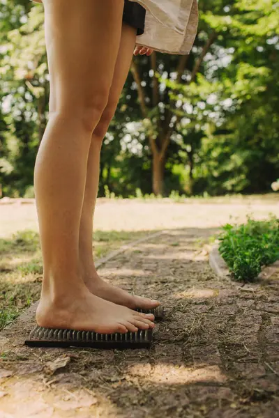 stock image Cropped shot of unrecognizable woman standing barefoot on a wooden Sadhu board with nails during concentration meditation practice outdoors. Part of a series.