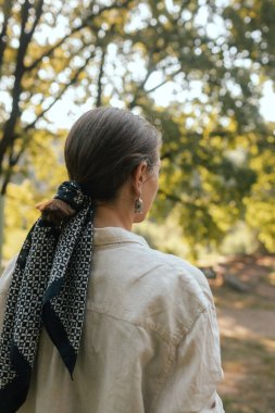 Parkta ileriye bakan bir kadının arkası. Dikkatli meditasyon konsepti. Sağlıklı olmak. Odak bulanıklığı ve gürültü etkisi yok. Dizinin bir parçası.