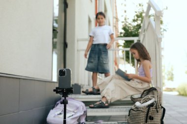 Çok ırklı ortaokul. Kızlar tiktok için video çeker ve okul bahçesinde telefon ve kulaklık kullanır. Alfa Geni. Dizinin bir parçası. Eğitimi ve UGC 'yi kabul et.