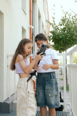 Çok ırklı ortaokul. Kızlar tiktok için video çeker ve okul bahçesinde telefon ve kulaklık kullanır. Alfa Geni. Dizinin bir parçası. Eğitimi ve UGC 'yi kabul et.