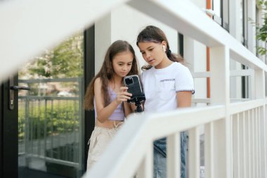 Çok ırklı ortaokul. Kızlar tiktok için video çeker ve okul bahçesinde telefon ve kulaklık kullanır. Alfa Geni. Dizinin bir parçası. Eğitimi ve UGC 'yi kabul et.