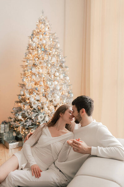 Young woman hugs her beloved husband giving him a gift on this special day. Concept of gifts for birthdays, Christmas, Valentine's Day and Men's Day. Modern living room interior. . Part of a series.