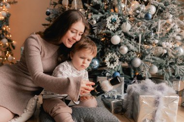 Mutlu, bekar bir anne, Noel ağacının yanında, oturma odasında oğluna yeni yıl hediyesi verir. Yalnız ebeveynlik kavramı ve yeni yıl için hediyeler, anneler günü ve babalar günü. Modern iç mekan. Bir serinin parçası.